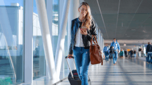 female traveling healthcare professional walks through the airport looking at her device